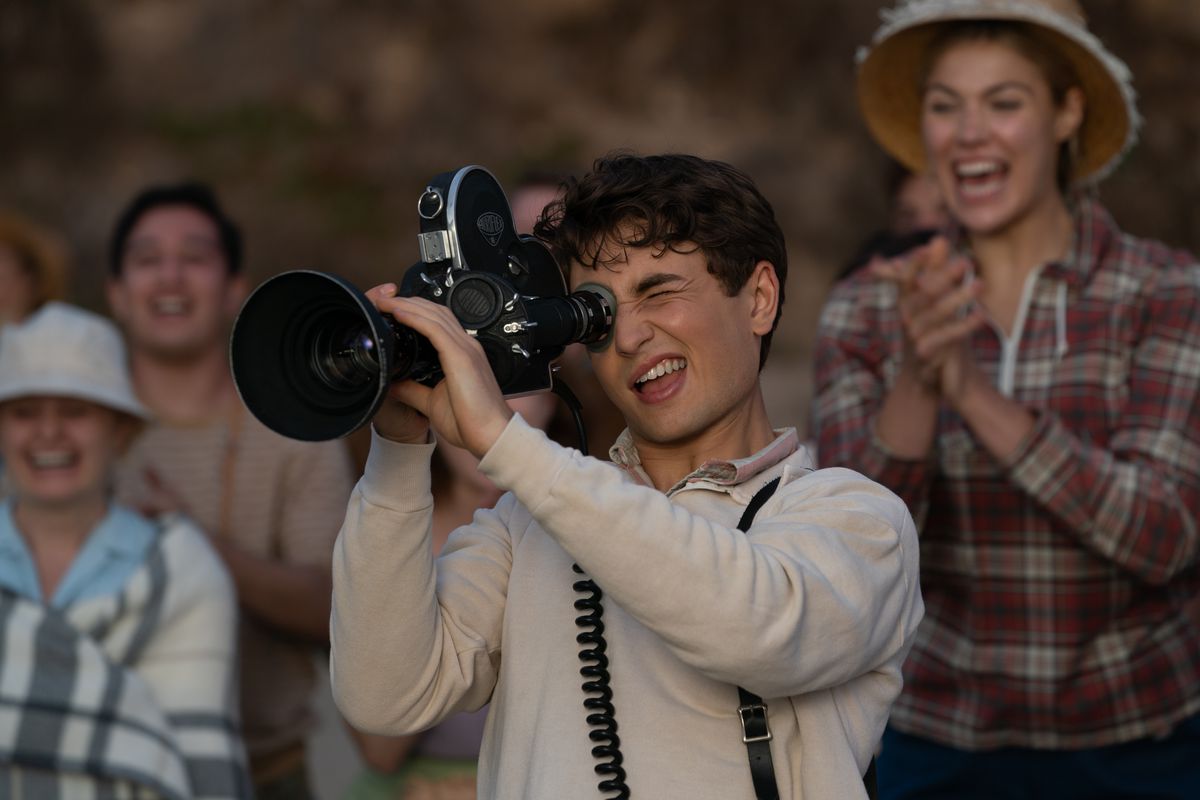 L'adolescent Sammy Fabelman (Gabriel LaBelle) sourit en pointant une grande caméra vers quelque chose hors écran tandis que les adultes derrière lui sourient et applaudissent dans The Fabelmans