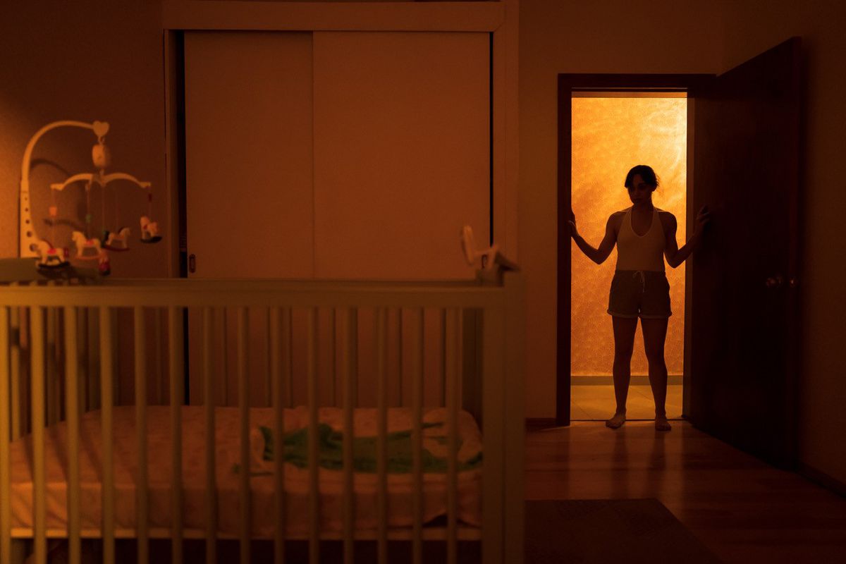Une silhouette de femme se tient devant la porte d'une crèche éclairée par derrière dans le film d'horreur Huesera : The Bone Woman