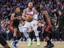 Le garde des New York Knicks Jalen Brunson passe devant le garde des Miami Heat Kyle Lowry (7) et l'attaquant Jimmy Butler (22) lors du match 5.