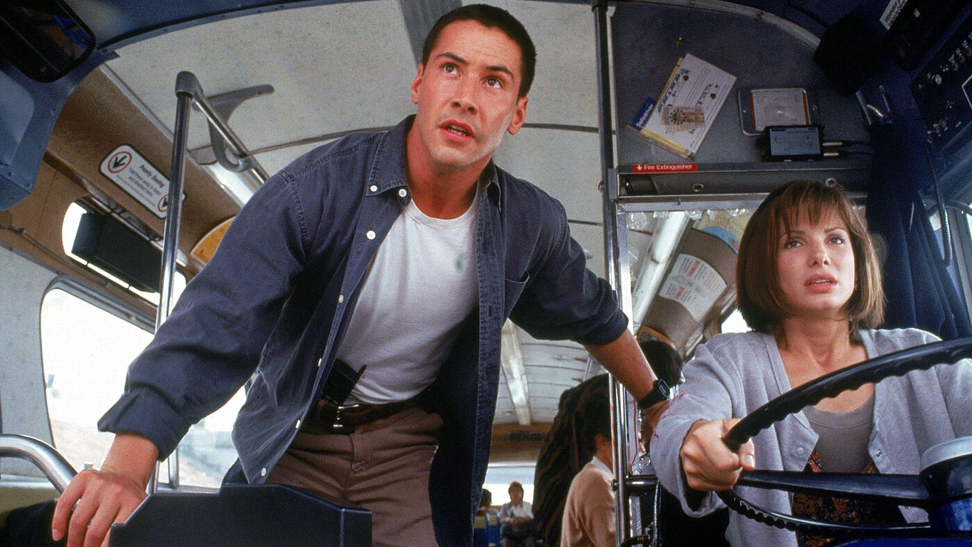 (De gauche à droite) Keanu Reeves dans le rôle de Jack Traven et Sandra Bullock dans le rôle d'Annie Porter, alors que cette dernière conduit le bus dans Speed