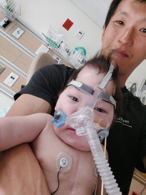 Davis Lim avec son bébé d'un an Theo, un jour après que les médecins ont pratiqué une trachéotomie pour l'aider à respirer.