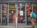 Un homme se tient devant le magasin Nordstrom, fermé pour les achats en magasin au centre-ville de Toronto, le 23 novembre 2020.