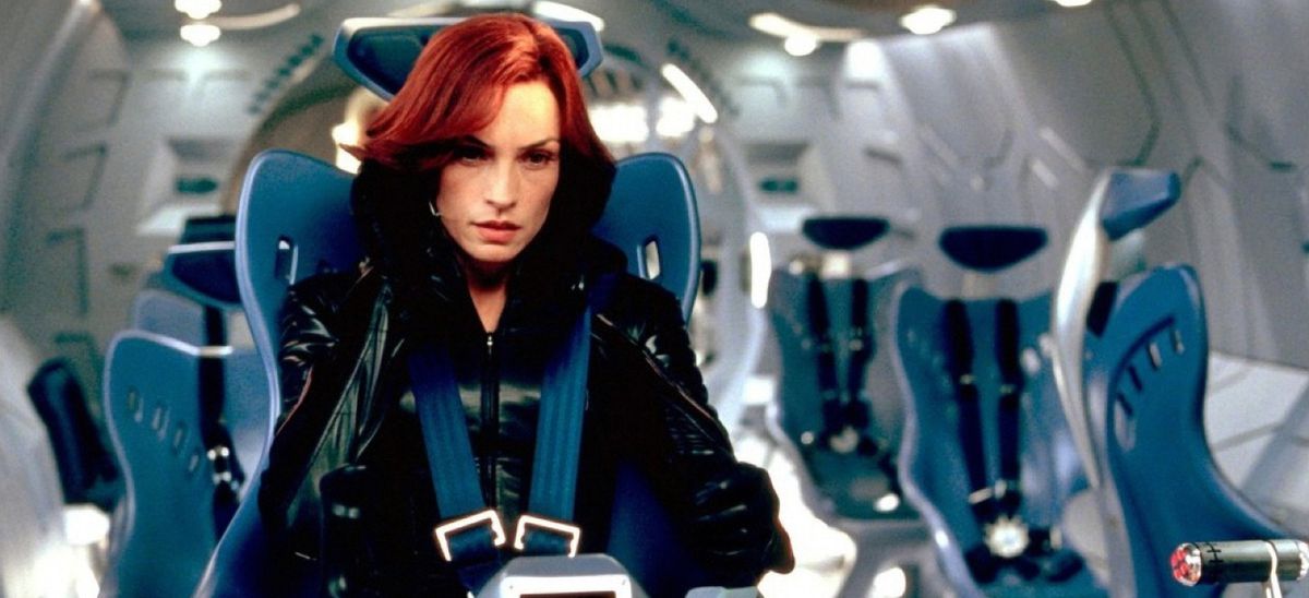 Jean Gray (Famke Janssen) est assis dans l'avion des X-Men, entouré de sièges bleus étincelants et de murs argentés, dans X2 : X-Men United