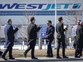 Des membres de l'Air Line Pilots Association manifestent au milieu des négociations contractuelles devant le siège social de WestJet à Calgary le 31 mars.