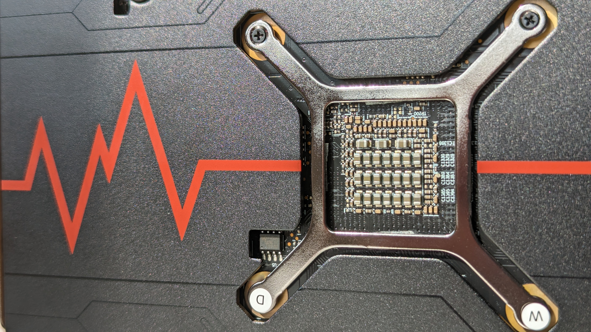 Examen AMD Radeon RX 7600 : gros plan de l'arrière de la carte graphique, avec un graphique d'impulsion rouge sur la plaque arrière et un support argenté exposé