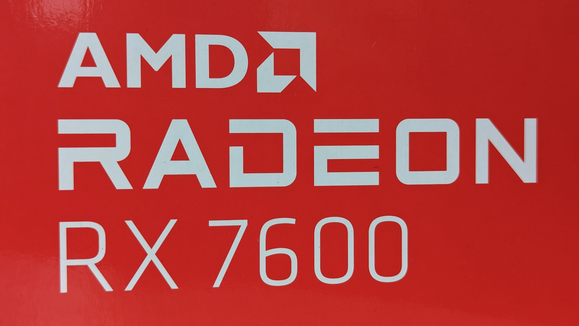 Test de l'AMD Radeon RX 7600 : Le texte blanc officiel 'AMD Radeon RX 7600' sur fond rouge