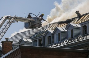 Les pompiers à la fin d'un camion à échelle pulvérisent le toit d'un immeuble en feu