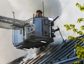 Des pompiers au bout d'un camion-échelle combattent un incendie sur le toit d'un immeuble ancien