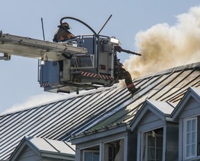 Un pompier donne des coups de pied sur le toit alors qu'il lutte contre un incendie à l'ancien Monastère du Bon-Pasteur à Montréal le 26 mai 2023.