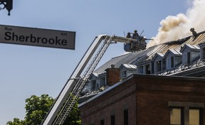 Les pompiers à la fin d'un camion à échelle pulvérisent le toit d'un immeuble en feu