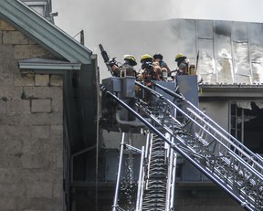Des pompiers au bout d'un camion-échelle combattent un incendie sur le toit d'un immeuble ancien