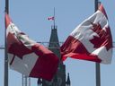 Les drapeaux canadiens flottent en berne sur la tour de la Paix et autour de la ville le lundi 31 mai 2021 à Ottawa.  Les drapeaux ont été abaissés indéfiniment pour reconnaître la découverte de restes d'enfants à l'ancien pensionnat indien de Kamloops.