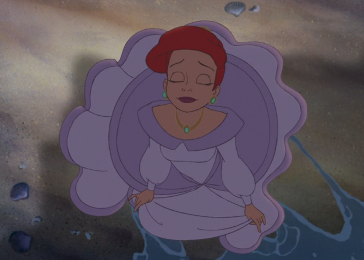 Une Ariel adulte ferme les yeux et plonge un pied dans l'eau de mer