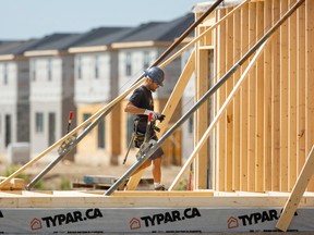 Un travailleur de la construction encadre une nouvelle maison à London, en Ontario.