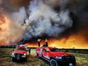Les pompiers se tiennent sur un camion Kamloops Fire Rescue lors d'un incendie de forêt près de Fort St. John, Colombie-Britannique, Canada, le 14 mai 2023.