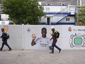Des travailleurs passent devant une affiche de Vinicius Junior du Real Madrid