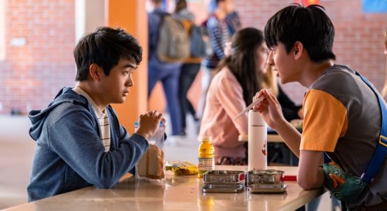 Two teenage boys sit across from each other at a cafeteria table; still from "American Born Chinese"