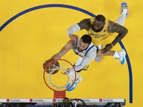 Le gardien des Golden State Warriors Stephen Curry tire le ballon contre l'attaquant des Los Angeles Lakers LeBron James.
