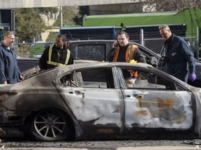 Un inspecteur des incendies criminels de la police examine des voitures incendiées sur un terrain à Montréal, au Québec, le vendredi 4 novembre 2022.