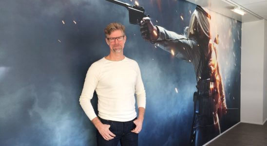 Lars Gustavsson stands in front of a large piece of artwork from Battlefield 1.