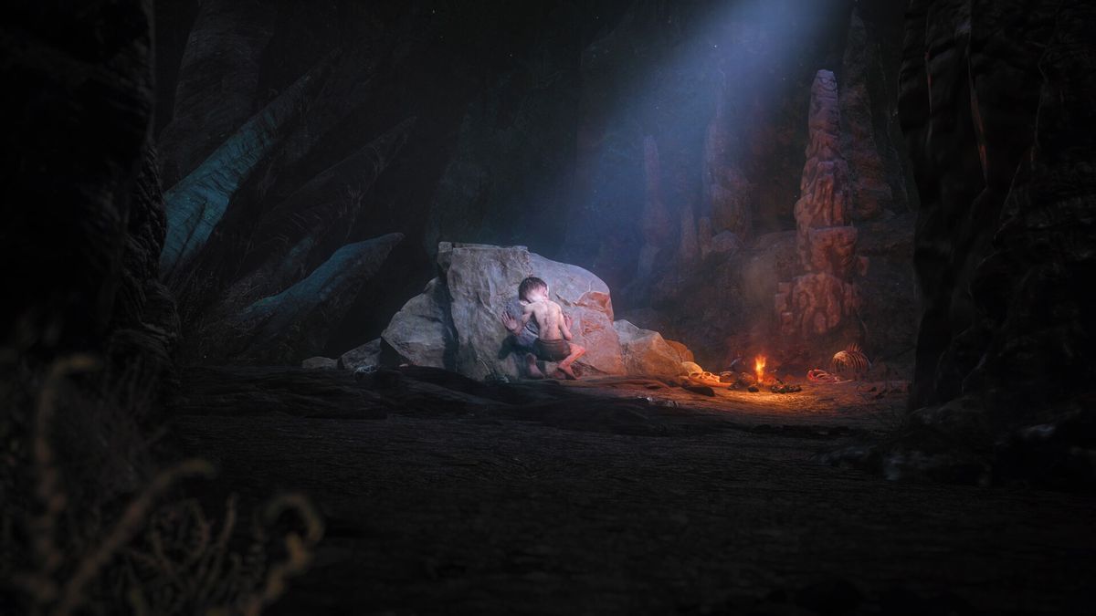 Dans une grotte sombre éclairée par un petit feu et un faisceau de lumière du ciel, Gollum s'accroupit dos à la 
