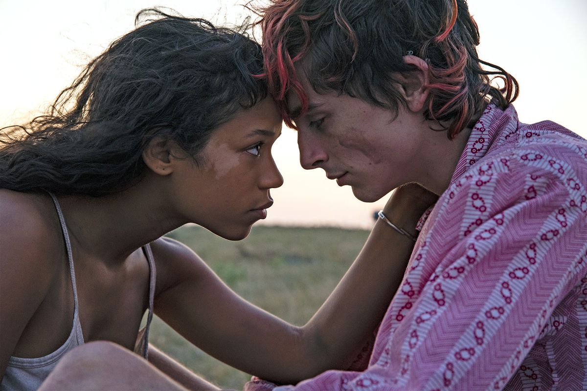 Une jeune femme (Taylor Russell) place son front contre un jeune homme (Timothee Chalamet) avec des mèches de teinture rose dans les cheveux.