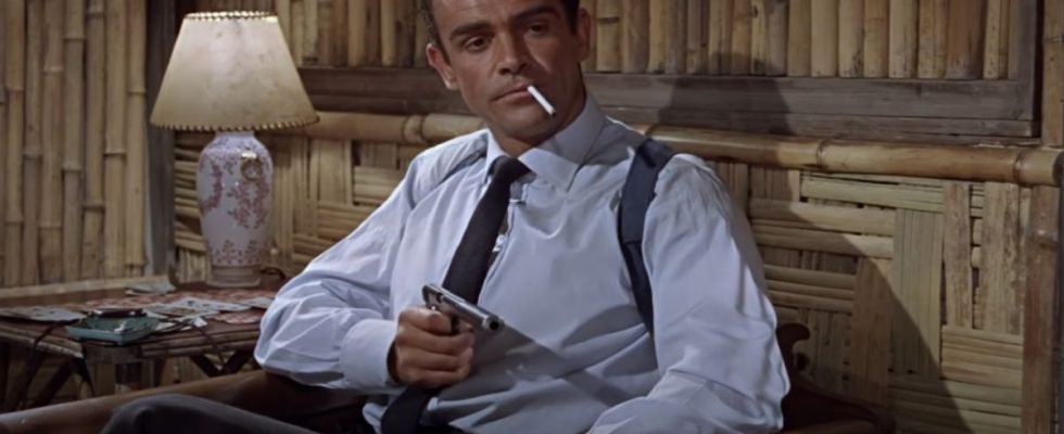 Sean Connery cooly aims his gun in his hotel room in Dr. No.