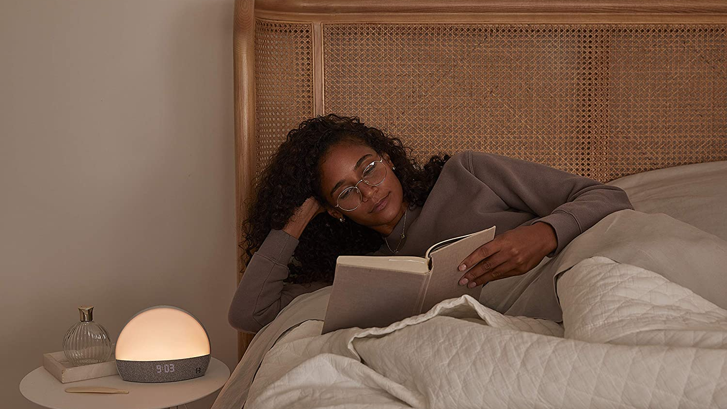 Une femme aux cheveux noirs bouclés lit au lit pour se détendre avant de dormir