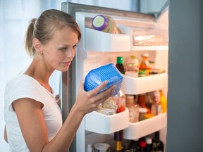 Est-ce toujours bien ?  Jolie jeune femme dans sa cuisine près du réfrigérateur, regardant la date de péremption d'un produit qu'elle a sorti de son réfrigérateur -