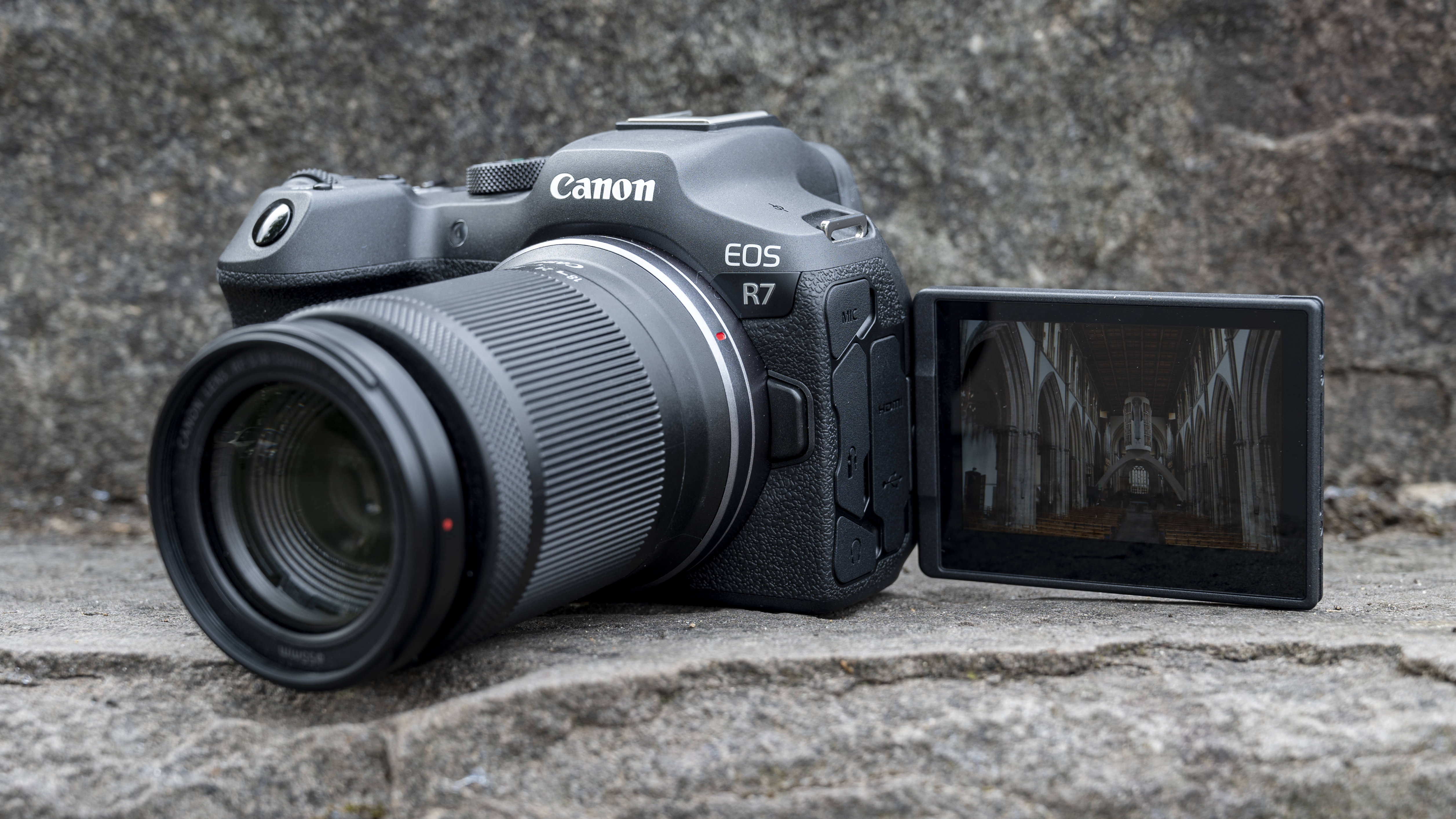 L'appareil photo Canon EOS R7 posé sur une marche de pierre