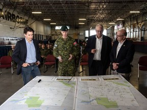 Le premier ministre Justin Trudeau (de gauche à droite), le colonel Ben Schmidt, le député Randy Boissonnault et le député Bill Blair rencontrent des membres des Forces armées canadiennes qui participent aux incendies de forêt en Alberta, à Edmonton le 15 mai 2023.
