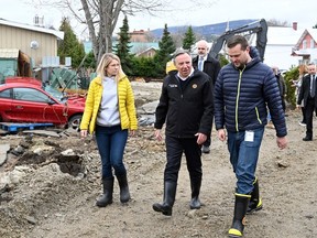 Le premier ministre du Québec, François Legault, discute avec le maire de Baie-St-Paul, Michael Pilote, alors qu'ils visitent le site d'une importante inondation printanière, le mercredi 3 mai 2023 à Baie-Saint-Paul.  La députée locale Kariane Bourassa, à gauche, regarde.