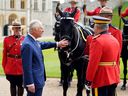 Le roi Charles III de Grande-Bretagne (2L), est officiellement présenté avec 'Noble', un cheval qui lui a été donné par la Gendarmerie royale du Canada (GRC) plus tôt cette année, alors qu'il accepte officiellement le rôle de commissaire en chef de la GRC au cours de une cérémonie dans le quadrilatère du château de Windsor, à l'ouest de Londres, le 28 avril 2023.