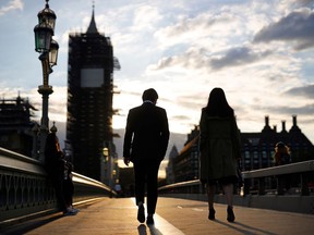 Un couple traverse le pont de Westminster alors que le soleil se couche à côté du Palais de Westminster.