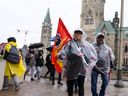 Des membres de l'Alliance de la Fonction publique du Canada (AFPC) marchent sous la pluie sur une ligne de piquetage à l'extérieur du Cabinet du Premier ministre et du Conseil privé, en face de la Colline du Parlement, alors que les travailleurs du plus grand syndicat de la fonction publique fédérale du Canada sont en grève à travers le pays à Ottawa.