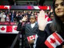 De nouveaux Canadiens prêtent serment lors d'une cérémonie spéciale de citoyenneté tenue à Ottawa avant un match de hockey entre les Sénateurs d'Ottawa et les Flames de Calgary.  Le Canada a récemment annoncé qu'il augmenterait ses objectifs annuels en matière d'immigration. 