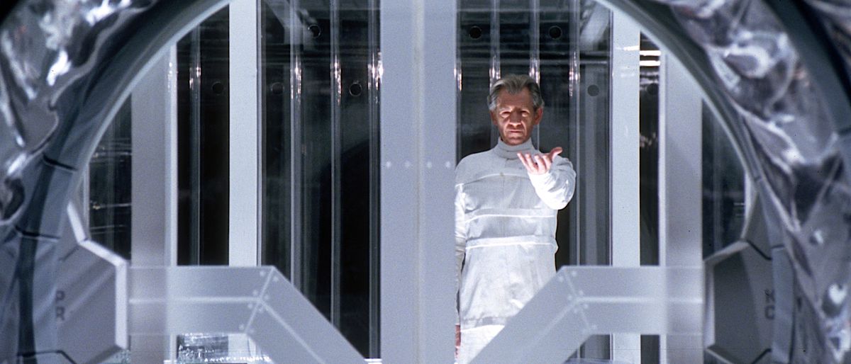 Magneto (Ian McKellan), tout blanc, se tient dans sa prison de verre dans X2: X-Men United et lève la main, paume vers le haut, alors qu'il commence son évasion