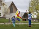 Deux enfants saluent des véhicules tout en tenant un drapeau Pride en face de l'église de la congrégation réformée des Pays-Bas à Norwich, en Ontario, le mercredi 3 mai 2023. Le canton du sud de l'Ontario a voté le mois dernier pour interdire les drapeaux Pride sur la propriété municipale.