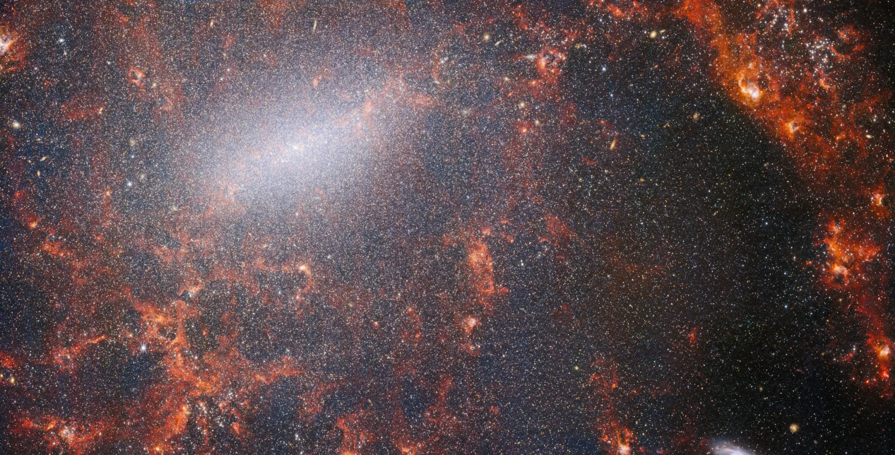 Un entrelacs délicat de poussière et d'amas d'étoiles brillantes traverse cette image du télescope spatial NASA/ESA/CSA James Webb.  Cette vue de l'instrument NIRCam de Webb est parsemée de la population massive d'étoiles de la galaxie, la plus dense le long de sa barre centrale brillante, ainsi que de nuages ​​​​de gaz rouges brûlants illuminés par de jeunes étoiles à l'intérieur.  Ces étoiles scintillantes appartiennent à la galaxie spirale barrée NGC 5068, située à environ 17 millions d'années-lumière de la Terre dans la constellation de la Vierge.  Ce portrait de NGC 5068 fait partie d'une campagne visant à créer un trésor astronomique, un référentiel d'observations de la formation d'étoiles dans les galaxies voisines.  Les joyaux précédents de cette collection peuvent être vus ici et ici.  Ces observations sont particulièrement précieuses pour les astronomes pour deux raisons.  La première est que la formation des étoiles sous-tend de nombreux domaines de l'astronomie, de la physique du plasma ténu qui se trouve entre les étoiles à l'évolution de galaxies entières.  En observant la formation d'étoiles dans les galaxies voisines, les astronomes espèrent lancer des avancées scientifiques majeures avec certaines des premières données disponibles de Webb.  La deuxième raison est que les observations de Webb s'appuient sur d'autres études utilisant des télescopes, notamment le télescope spatial Hubble de la NASA/ESA et certains des observatoires au sol les plus performants au monde.  Webb a recueilli des images de 19 galaxies stellaires proches que les astronomes ont ensuite pu combiner avec des catalogues de Hubble de 10 000 amas d'étoiles, une cartographie spectroscopique de 20 000 nébuleuses d'émission stellaires du Very Large Telescope (VLT) et des observations de 12 000 nébuleuses sombres. , nuages ​​moléculaires denses identifiés par l'Atacama Large Millimeter/submillimeter Array (ALMA).  Ces observations couvrent le spectre électromagnétique et offrent aux astronomes une occasion sans précédent de reconstituer les détails de la formation des étoiles.  Cette image proche infrarouge de la galaxie est remplie par l'énorme rassemblement d'étoiles plus anciennes qui constituent le noyau de NGC 5068. La vision aiguë de NIRCam permet aux astronomes de regarder à travers le gaz et la poussière de la galaxie pour examiner de près ses étoiles.  Des nuages ​​de poussière denses et brillants se trouvent le long de la trajectoire des bras spiraux : ce sont des régions H II, des collections d'hydrogène gazeux où de nouvelles étoiles se forment.  Les étoiles jeunes et énergiques ionisent l'hydrogène qui les entoure ce qui, combiné à l'émission de poussières chaudes, crée cette lueur rougeâtre.  Les régions H II forment une cible fascinante pour les astronomes, et les instruments de Webb sont les outils parfaits pour les examiner, aboutissant à cette image. [Image Description: A close-in image of a spiral galaxy, showing its core and part of a spiral arm. At this distance thousands upon thousands of tiny stars that make up the galaxy can be seen. The stars are most dense in a whitish bar that forms the core, and less dense out from that towards the arm. Bright red gas clouds follow the twist of the galaxy and the spiral arm.] Liens NGC 5068 (image NIRCam+MIRI) NGC 5068 (image MIRI) Slider Tool (images MIRI et NIRCam) Vidéo : Vue panoramique de NGC 5068 Vidéo : Vues de Webb sur NGC 5068 (images MIRI et NIRCam) Vidéo : Zoom sur NGC 5068 