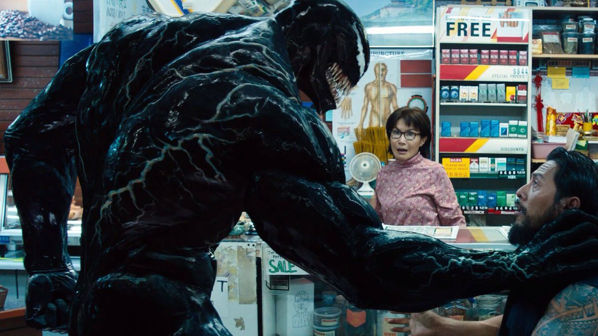 (LR) Venom (Tom Hardy) menaçant un cambrioleur devant Mme Chen (Peggy Lu) dans Venom.