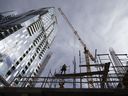 Un travailleur de la construction érige un échafaudage sur un immeuble en copropriété en construction au centre-ville de Montréal.  Le secteur de la construction manque de main-d'œuvre.