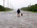 Un homme marche avec son chien sur une route inondée à Salvo, en Caroline du Nord, après le passage d'un ouragan.