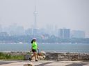 Winnie Wong promène son chien au parc Humber Bay Shores le 7 juin 2023, alors qu'une brume obscurcit la vue sur les toits de Toronto.  (Ernest Doroszuk, Toronto Sun)
