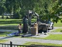 Les travailleurs réinstallent une statue de la reine Elizabeth qui a été renversée le jour de la fête du Canada 2021 à la suite de la découverte de tombes présumées non marquées dans un ancien pensionnat à Kamloops, en Colombie-Britannique
