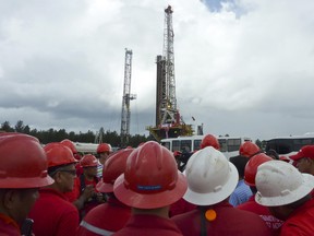 Des travailleurs du pétrole se rassemblent près d'un puits de pétrole au Venezuela.  La production de pétrole augmente dans le pays.