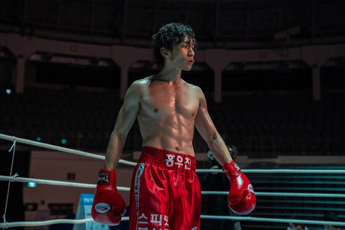 Hong Woo-jin se pavane sur le ring de boxe avec un maillot rouge et des gants rouges dans Bloodhounds.