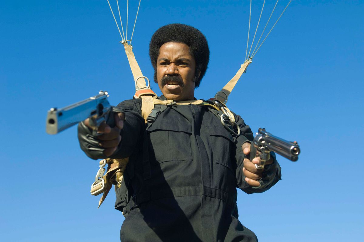 Michael Jai White tend deux pistolets tout en utilisant un parachute contre le ciel bleu dans Black Dynamite