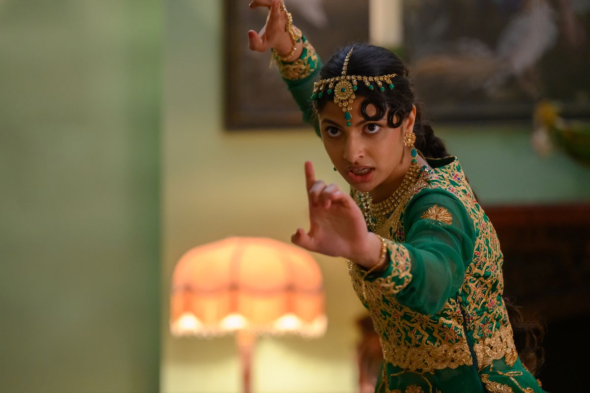 Ria, une adolescente pakistanaise vêtue d'une tenue de danse traditionnelle verte et dorée, tend les bras en position de combat.