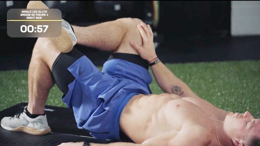 Noah en position couchée sur un tapis de yoga avec la cheville droite sur le genou gauche et la jambe gauche pliée en étirement du genou