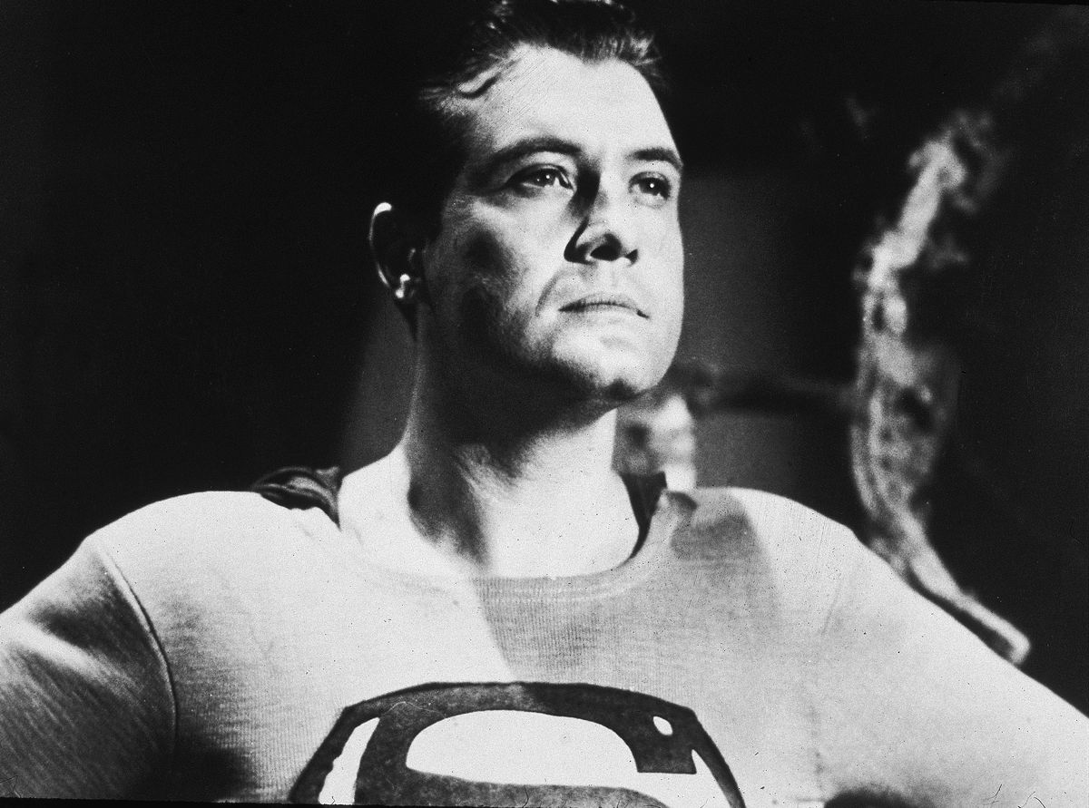 Une photo de portrait en noir et blanc de George Reeves en tant que Superman, alors qu'il regarde au loin de cette manière sereine de Superman. 